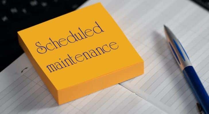 A sticky note reads "scheduled maintenance" sitting next to a pen.