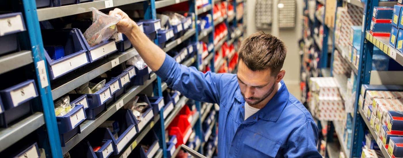 A mechanic is shown reaching for parts on a shelf.