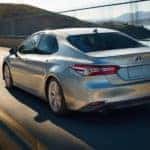 A silver 2020 Toyota Camry XLE Hybrid is shown from the rear leaving a used car dealer.