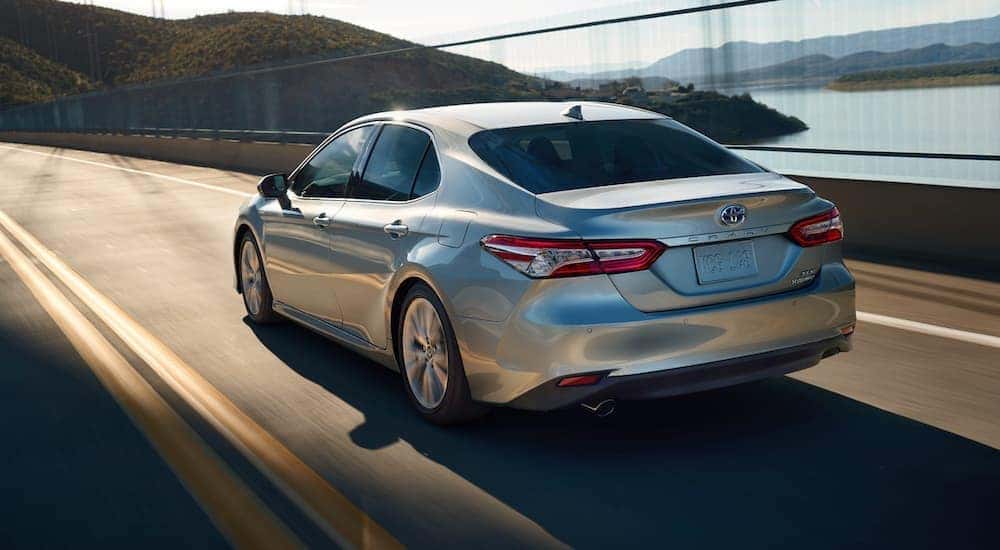 A silver 2020 Toyota Camry XLE Hybrid is shown from the rear leaving a used car dealer.