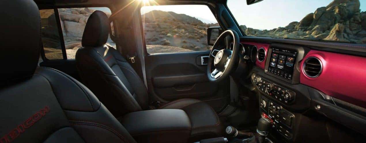 The black and red interior of a 2022 Jeep Gladiator shows the front seats and center console.