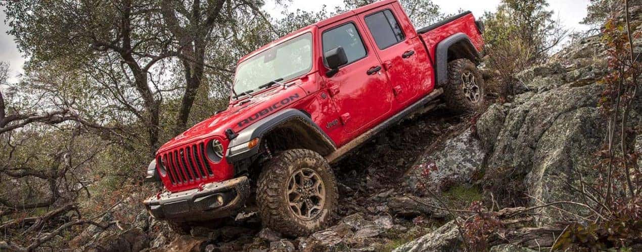A red 2022 Jeep Gladiator Rubicon is shown off-roading during a 2022 Jeep Gladiator vs 2022 Chevrolet Colorado comparison.