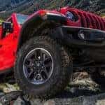 A red 2021 Jeep Wrangler Rubicon is shown off-roading during a Jeep Wrangler buyer's guide event.
