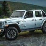 A silver 2023 Jeep Wrangler Sahara is shown parked on a mountain trail.