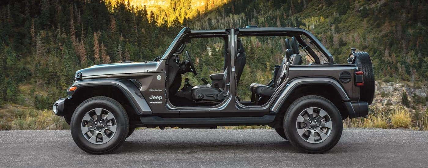 A grey 2022 Jeep Wrangler Sahara is shown from the side with the doors off.