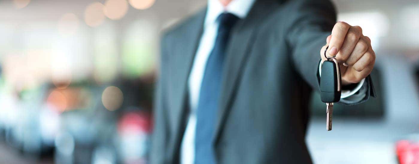 A salesman is shown holding a car key.