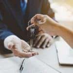 A customer is shown handing a car key to a salesman.