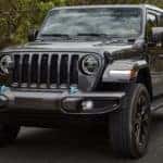 A grey 2022 Jeep Wrangler 4xe is shown from the front driving on an open road.