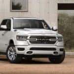 A white 2020 Ram 1500 is shown from the front parked in front of a barn.