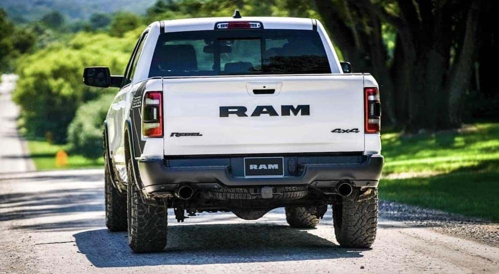 A white 2021 Ram 1500 is shown driving from the rear after getting a Ram truck lease.