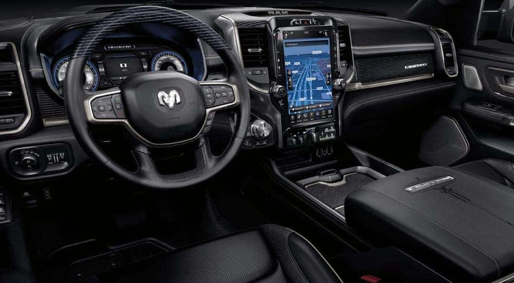 The black interior of a 2021 Ram 1500 shows the steering and infotainment screen.