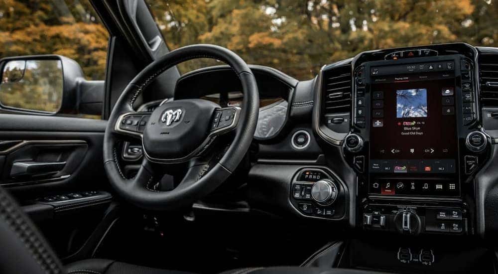 The black interior of a 2022 Ram 1500 shows the steering wheel and infotainment screen.
