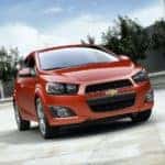 A red 2014 Chevy Sonic is shown parked from the front.