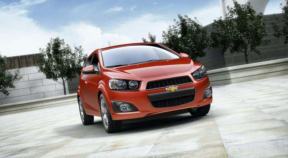 A red 2014 Chevy Sonic is shown parked from the front.