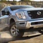 A silver 2021 Nissan Titan XD is shown driving of a dirt trail.