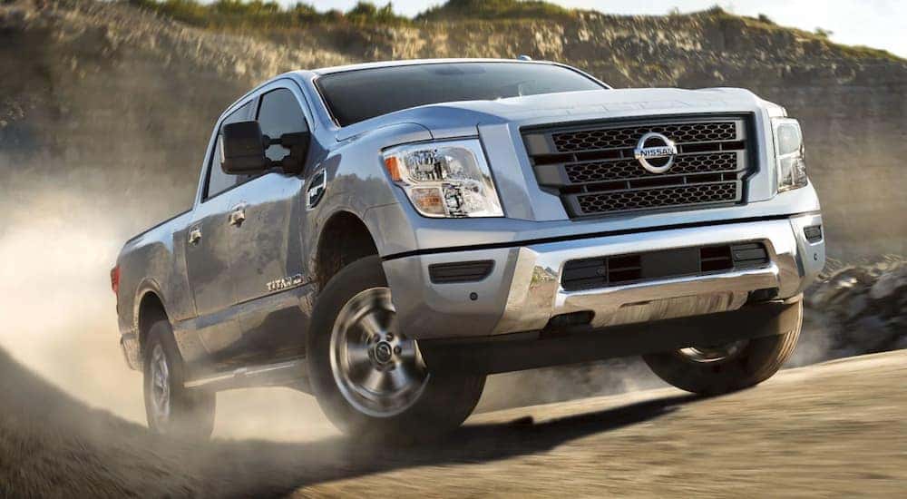 A silver 2021 Nissan Titan XD is shown driving of a dirt trail.