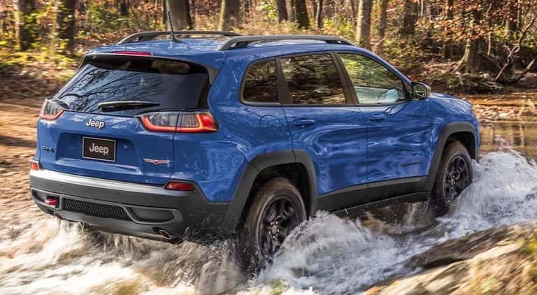 A blue 2021 Jeep Cherokee is shown from the rear off-roading after searching for a used Jeep Cherokee.