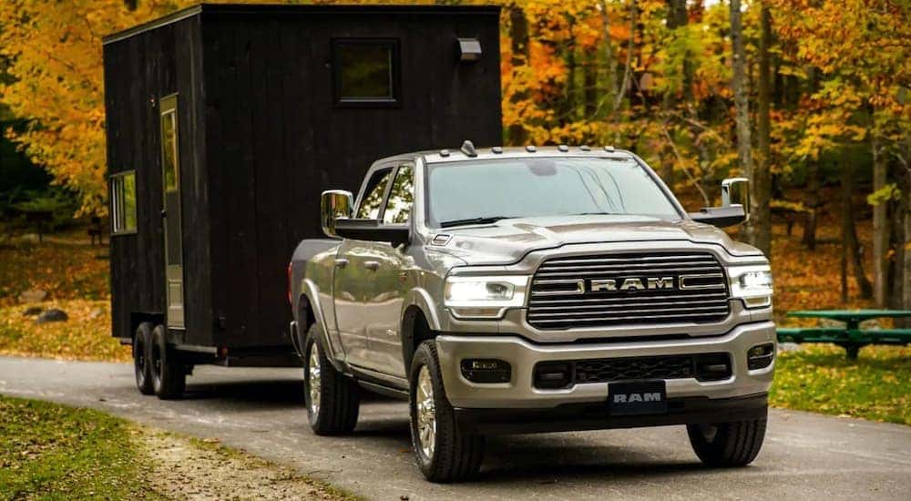 A tan 2019 Ram 2500 is shown towing a black trailer.