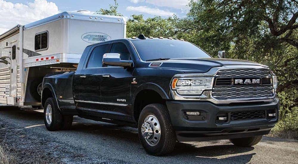 A black 2019 Ram 3500 is shown from the front towing a large camper after searching used trucks near me.