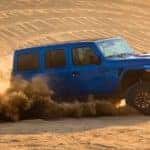 A blue 2021 Jeep Wrangler Rubicon 392 is shown from the side while driving through the desert.