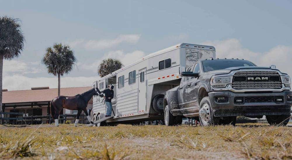 A grey 2022 Ram 3500 is shown towing a horse trailer.