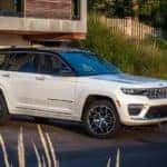 A white 2023 Jeep Grand Cherokee is shown parked in a driveway.