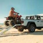 A silver 2022 Jeep Gladiator is shown from behind while being loaded with an ATV after leaving a dealer that advertised having a Jeep Gladiator for sale.