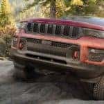 A red 2022 Jeep Grand Cherokee Trailhawk is shown from the front while off-roading.