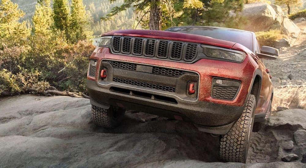 A red 2022 Jeep Grand Cherokee Trailhawk is shown from the front while off-roading.