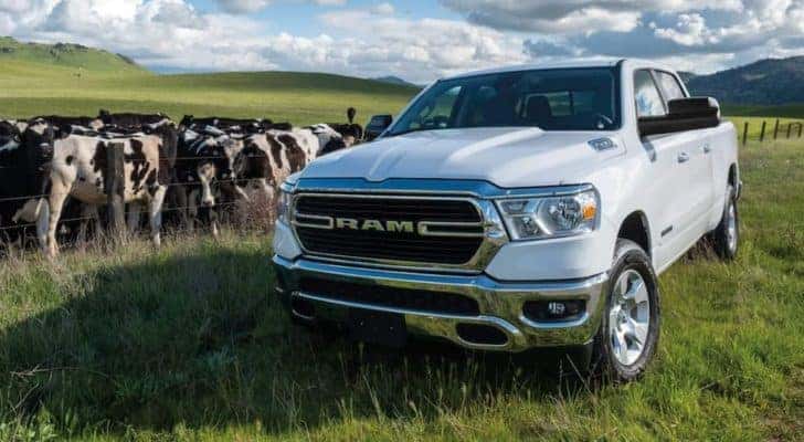 A popular used Ram truck for sale, a white 2021 Ram 1500, is shown parked in a field.