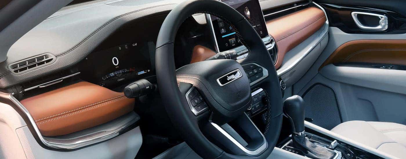 The grey and brown interior of a 2022 Jeep Compass shows the steering wheel and dashboard.