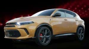 A yellow 2023 Dodge Hornet is shown angled left on a black and red background.