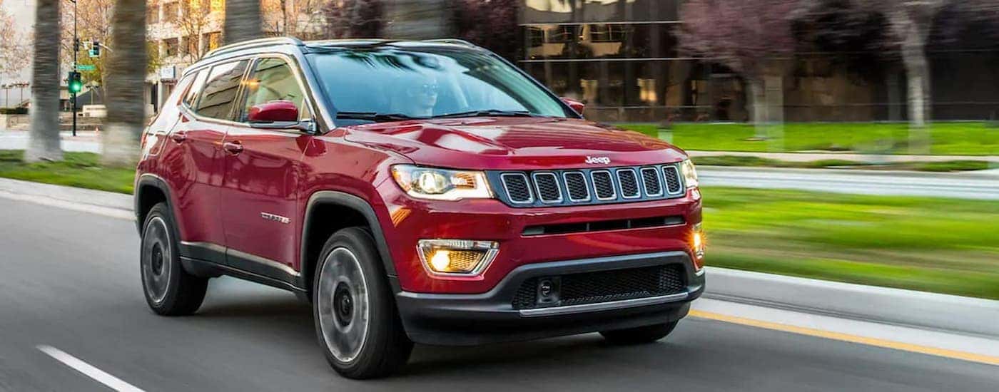 A red 2021 Jeep Compass is shown driving on a city street.