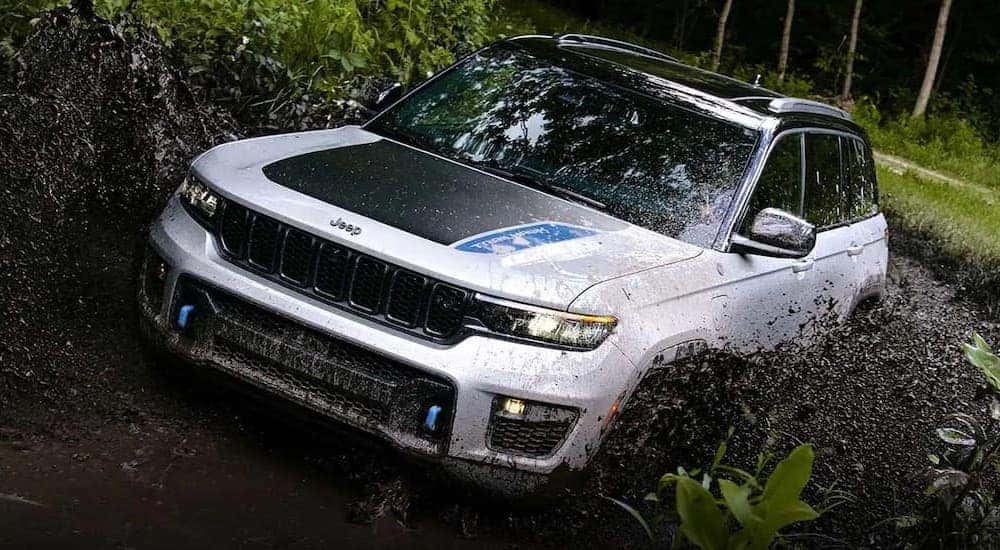 A white 2022 Jeep Grand Cherokee 4xe is shown from the front while driving through mud.