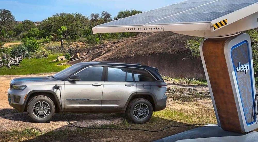 A silver 2022 Jeep Grand Cherokee 4xe is shown from the side while charging.