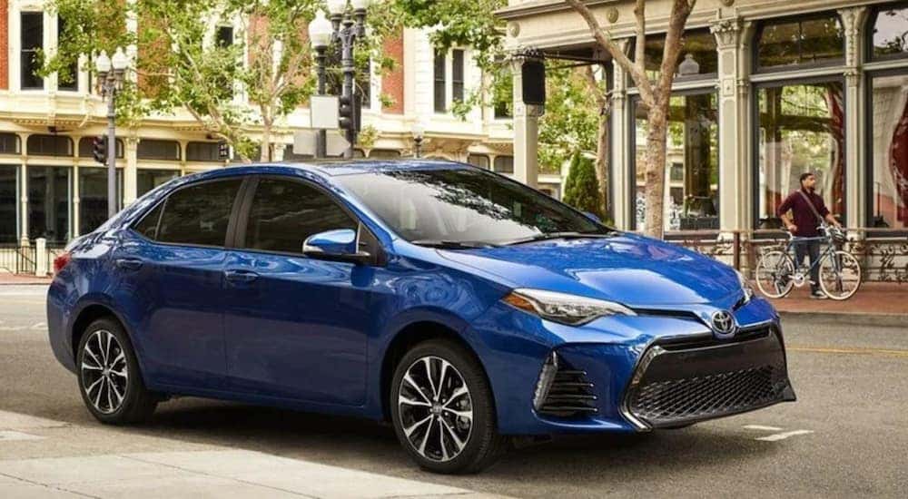 A popular fuel-efficient used car for sale, blue 2019 Toyota Corolla, is shown from the side parked in a city.