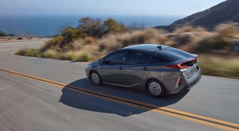 A grey 2020 Toyota Prius Prime is shown from the side driving on an open road.