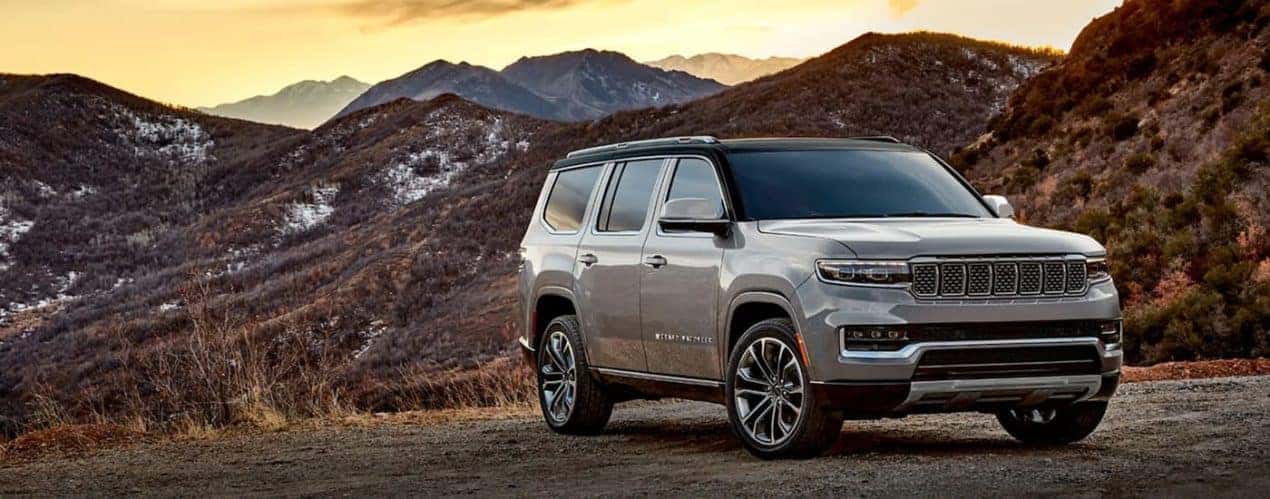 A grey 2023 Grand Wagoneer is shown parked with a rocky mountain view.