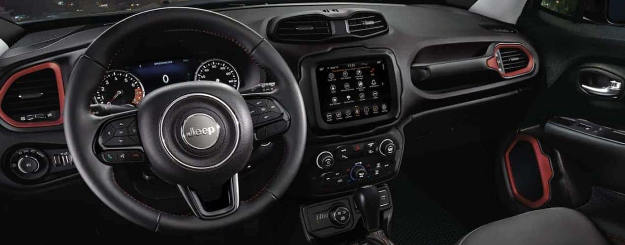 The black interior of a 2023 Jeep Renegade shows the steering wheel and infotainment screen.