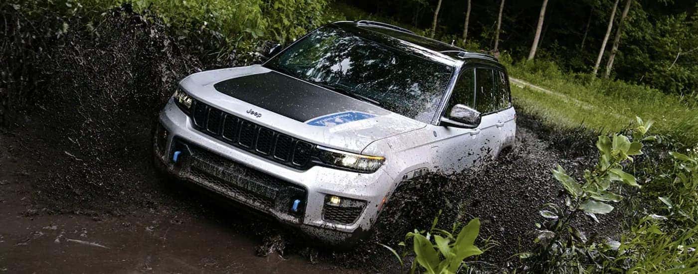 A white 2023 Jeep Wrangler 4xe is shown off-roading.