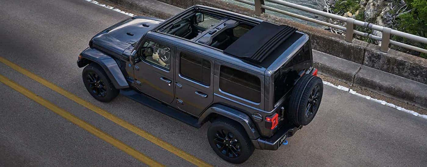 A grey 2023 Jeep Wrangler 4xe is shown driving on an open road after looking at Jeep Hybrids. 