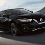 A black 2019 Nissan Maxima, a great Nissan lease option, is driving past hills outside Costa Mesa, CA.