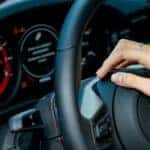 Porsche car dashboard. Porsche car steering wheel and female hand.