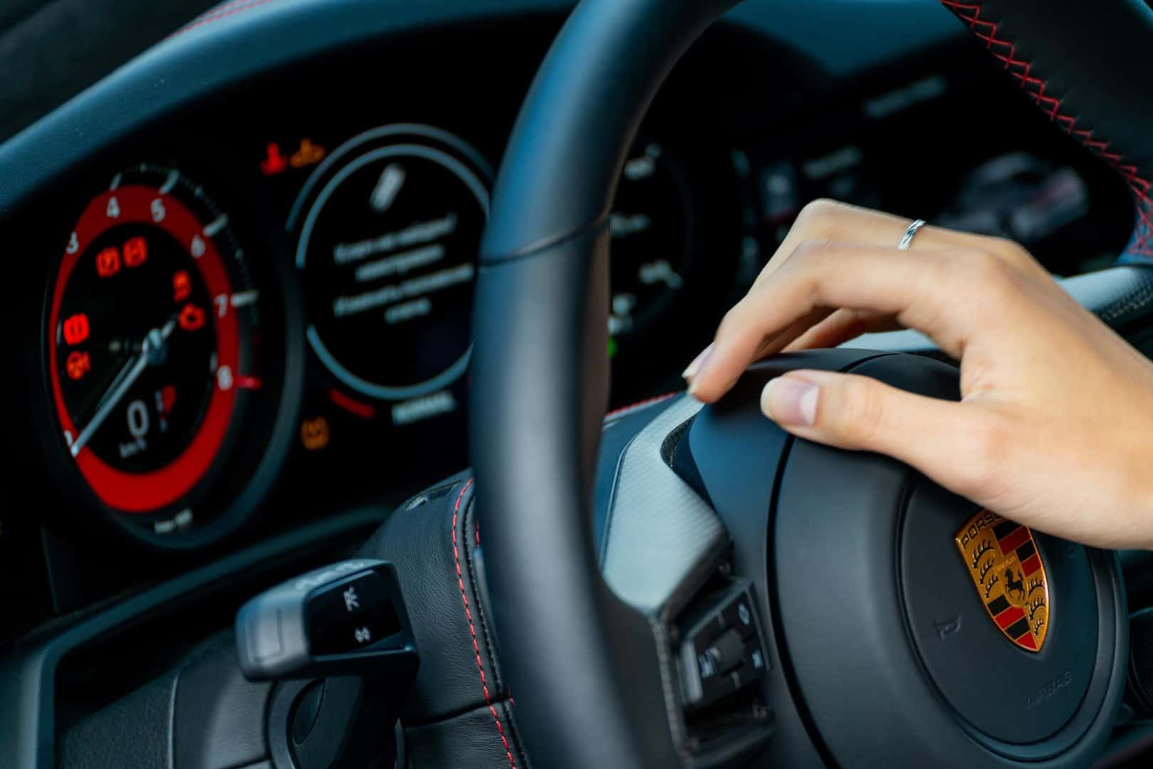 Porsche car dashboard. Porsche car steering wheel and female hand.