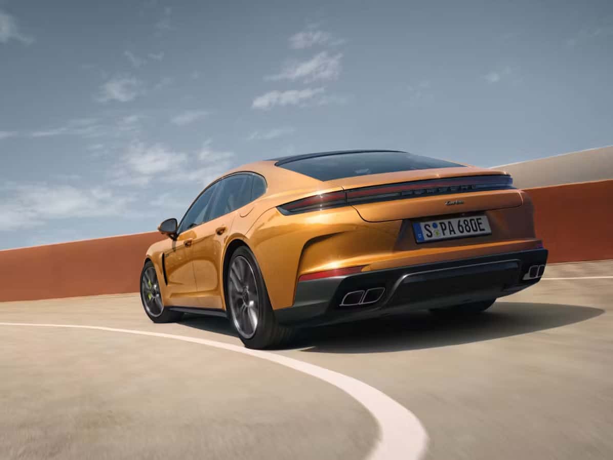 a goldish orange porsche panamera driving in a parking garage into the top area
