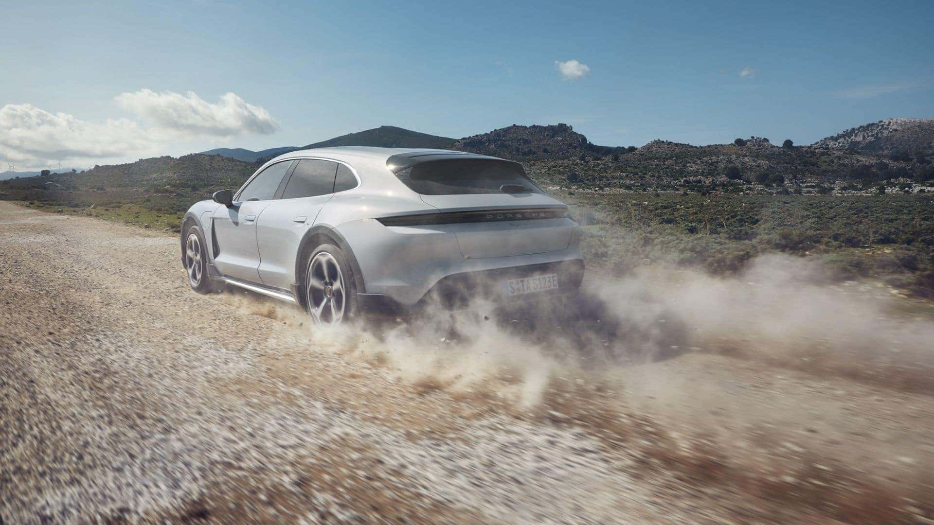 2025 porsche taycan in silver driving on a gravel road in the countryside