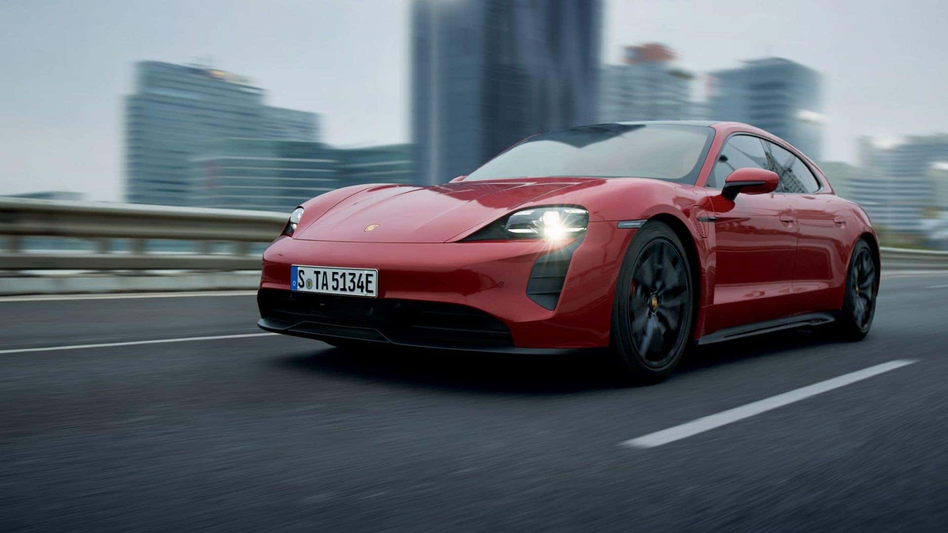 a red 2025 porsche taycan driving in the city