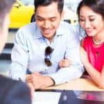 Couple signing sales contract for car at dealership