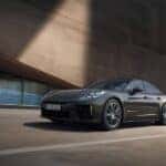 The Porsche Panamera front angle view against a modern architectural backdrop, emphasizing its bold and elegant design