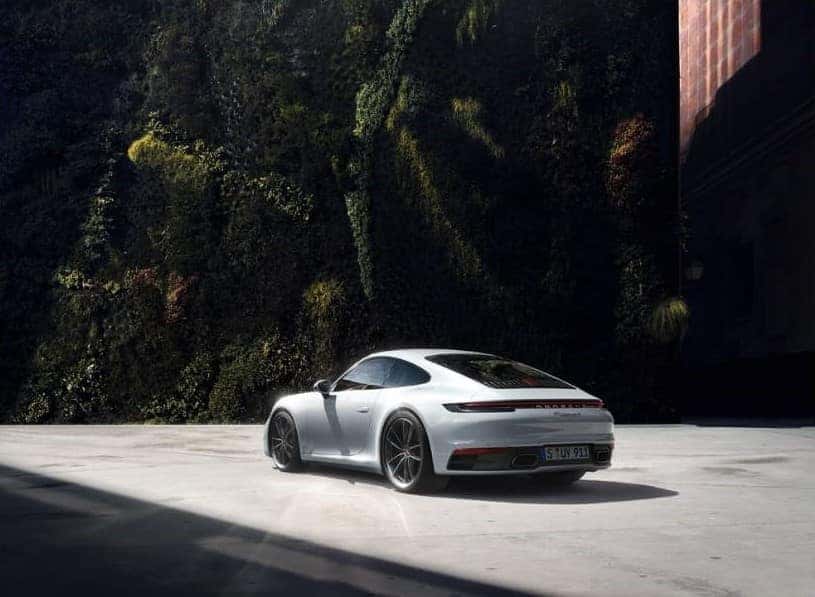 porsche 911 carrera 4s parked by green vegetation.